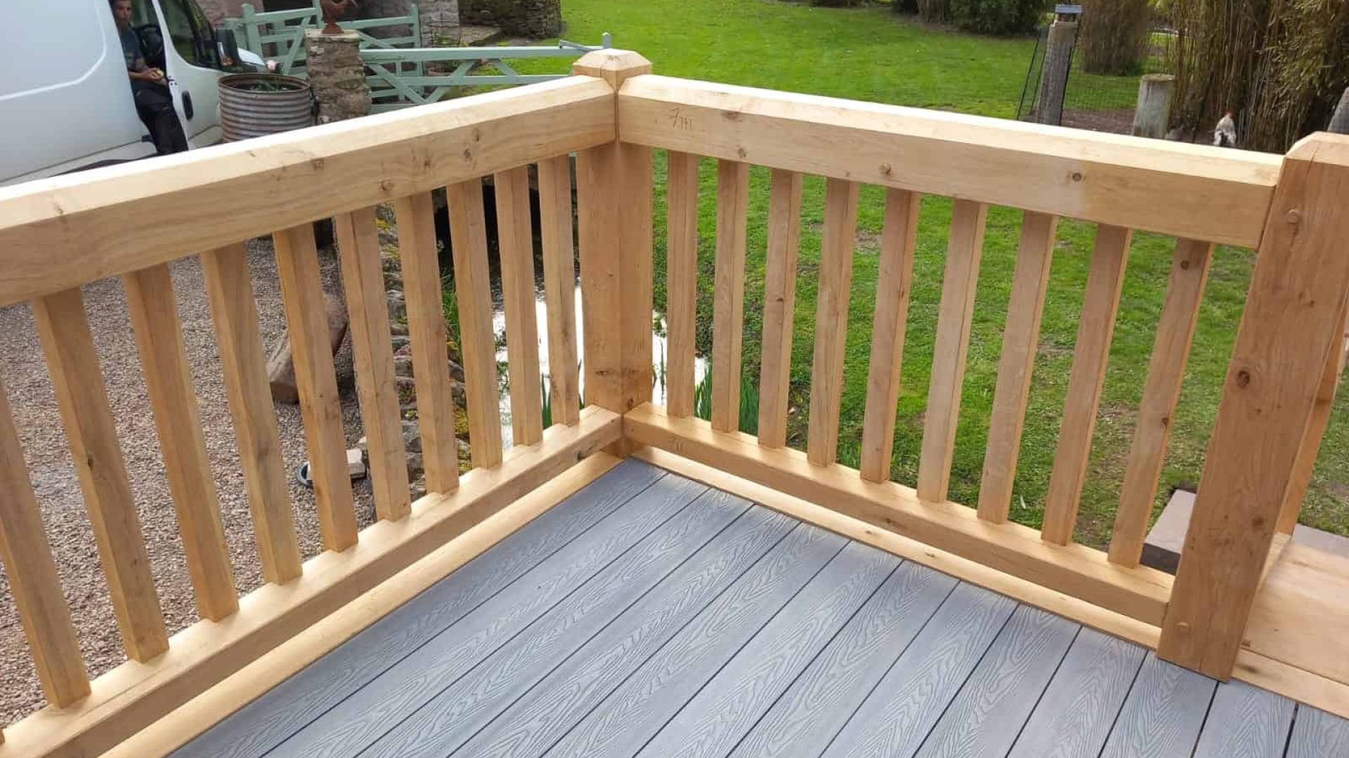 A new oak wooden deck with railings overlooking a garden.