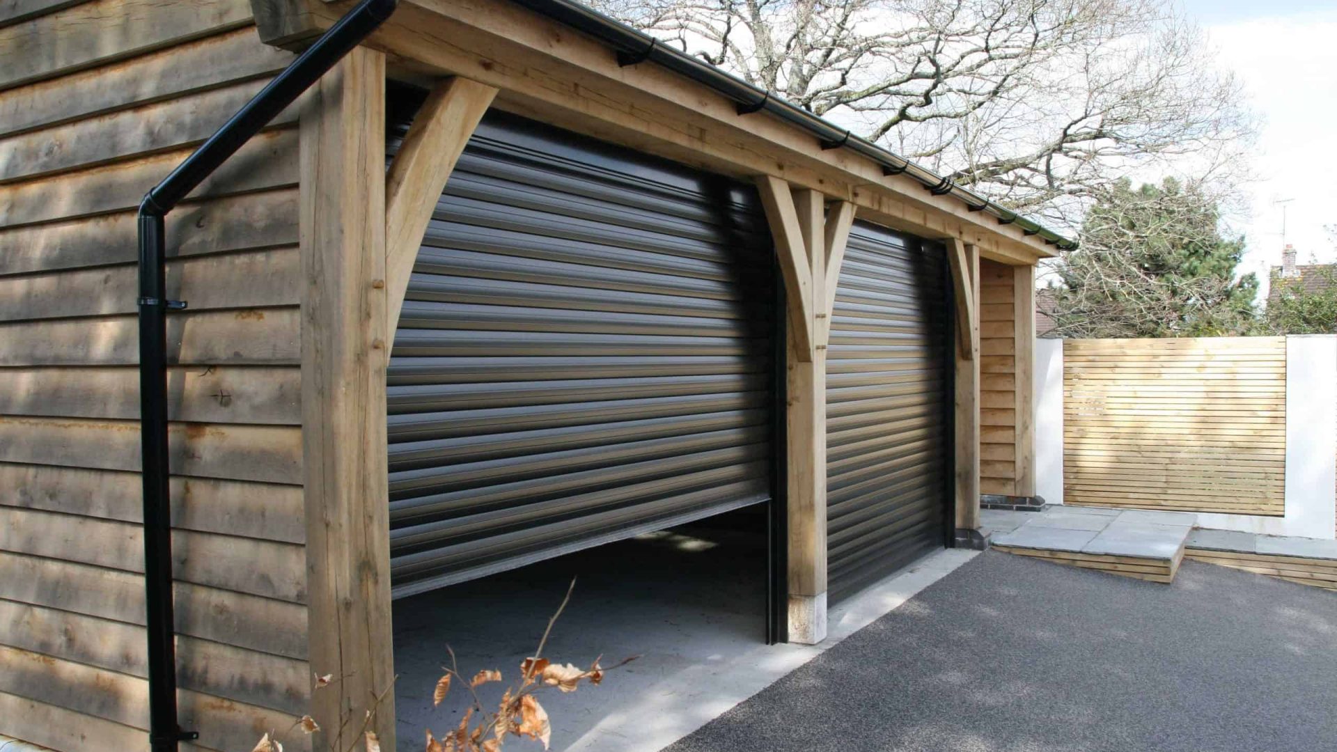 Oak wooden carport with a rolled-up metal door.